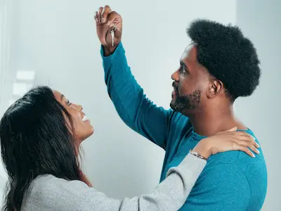 Man holding keys while couples smiles joyfully